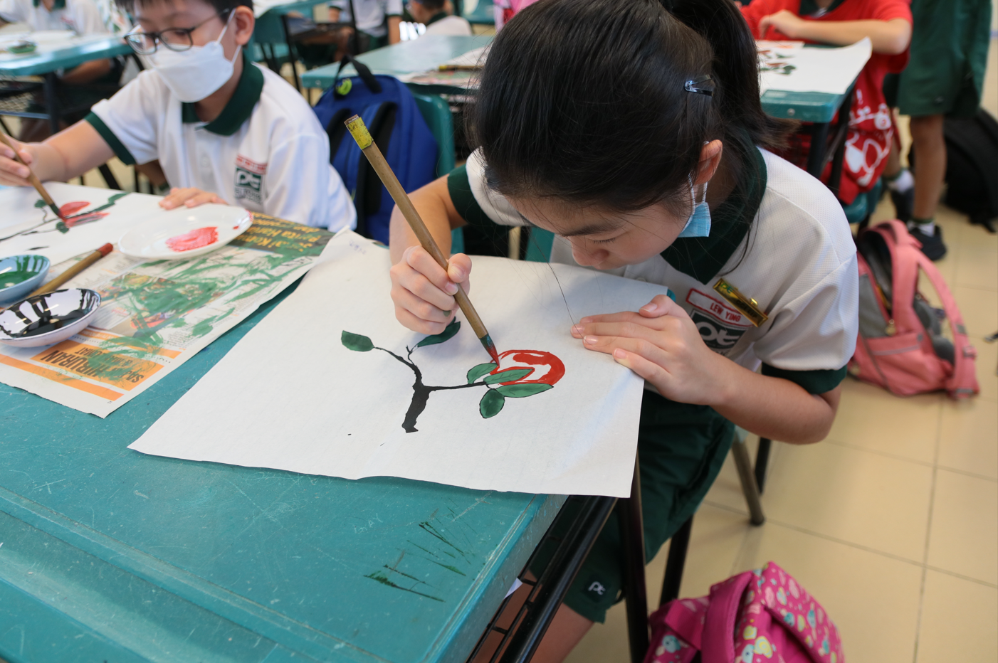 Student focused on creating a Chinese ink painting of a flower branch